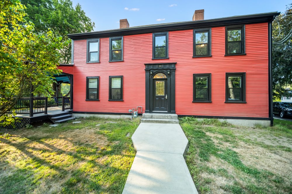 The finished house in red clapboard with black trim